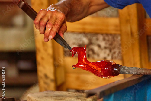 Murano glass blower holds a red hot glass horse sculpture