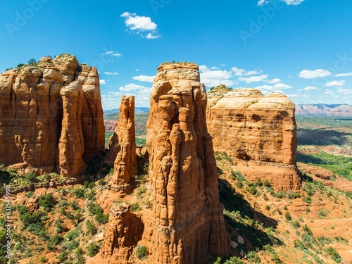 three tall rock formations with green and brown vegetation and bushes photo