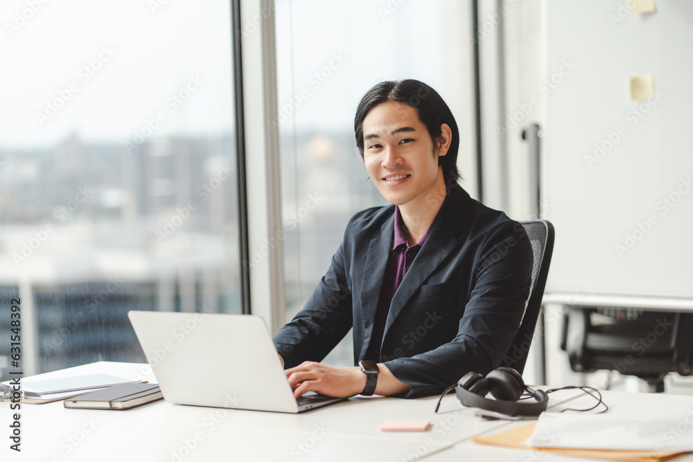 Asian businessman, successful trader, using laptop, working in modern office, looking at camera Asian businessman, successful trader, using laptop, working in modern office, looking at camera