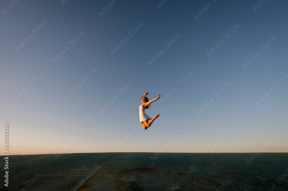 Silhouette of a beautiful woman jumping into the air against a stunning background