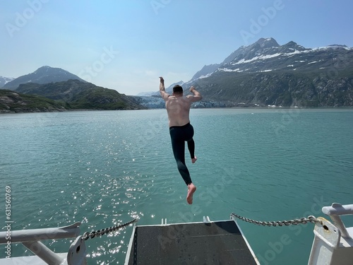 Canvas Print Jumping into frigid waters with a glacier in the background with no fear