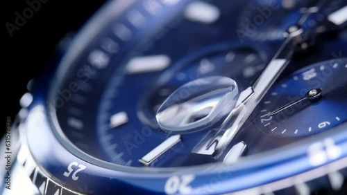 second hand ticking on a blue watch face. Men's chronograph watch in metal with sapphire crystal. closeup view of rotating watch, running second arrow. blue dial