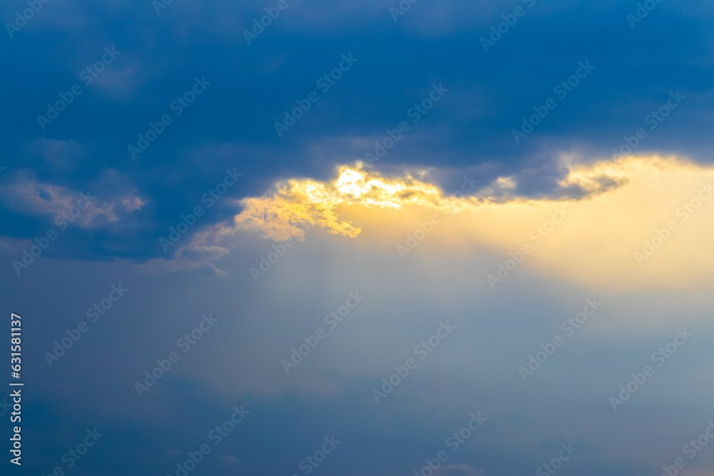 A narrow band of yellow golden clouds in the dark blue sky at sunset