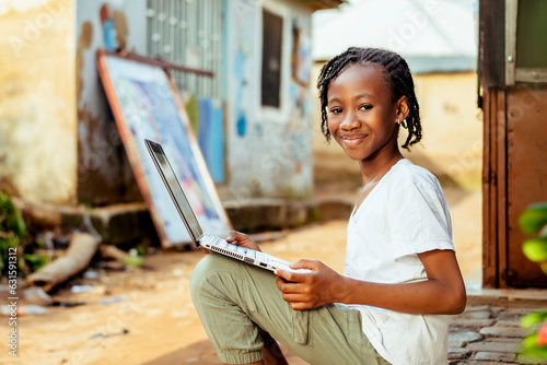 excited young African child using a laptop on the ground
