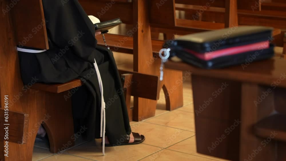 Fraile monje franciscano meditando rezando leyendo orando con la biblia en una capilla de oración en templo iglesia católica cristiana conociendo la palabra de Dios