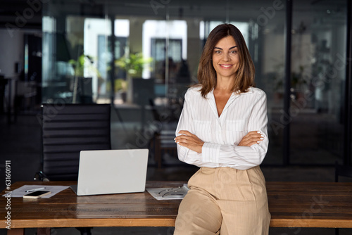 Beautiful hispanic senior business woman with crossed arms smiling at camera. European or latin confident mature good looking middle age leader female businesswoman on office background, copy space. photo