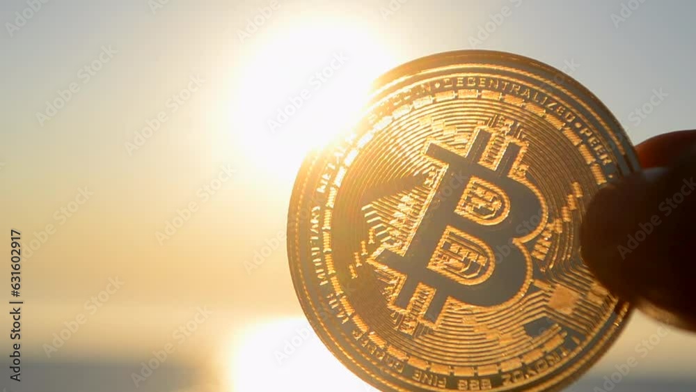 Bitcoin coin close up. Person holding Bitcoin coin in hand on background of sea, blue sky and shining sun at dawn and sunset. Concept cryptocurrency money cryptography cryptocurrencies bitcoins crypto