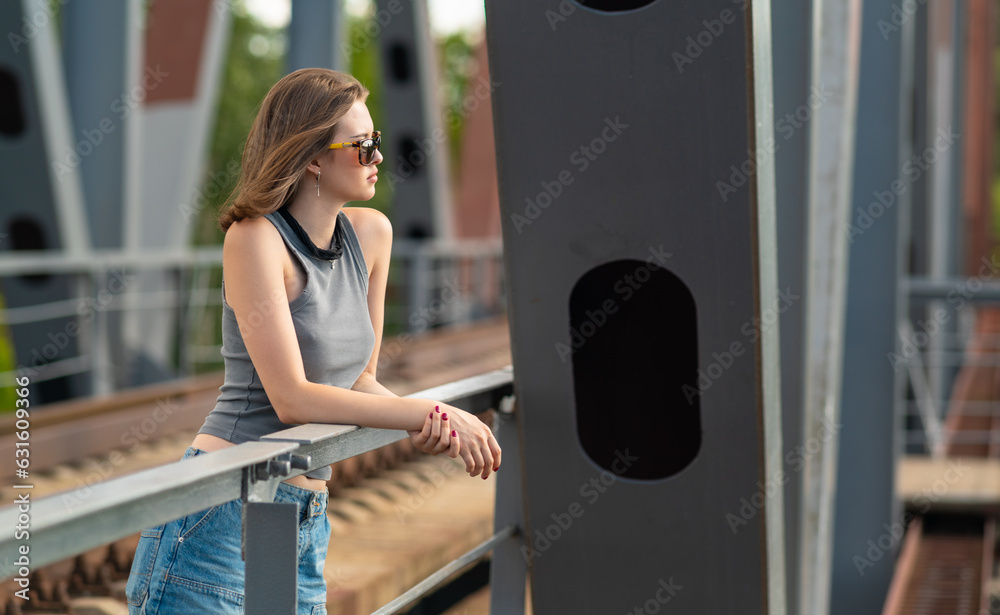 The girl stands on the railway bridge