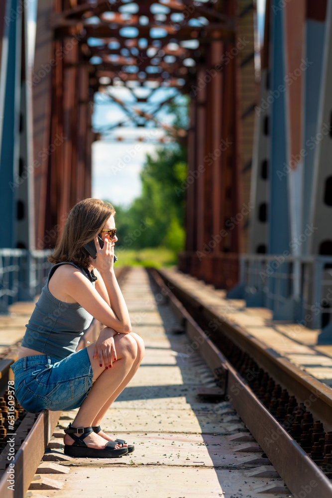 Young woman with phone sitting on rails