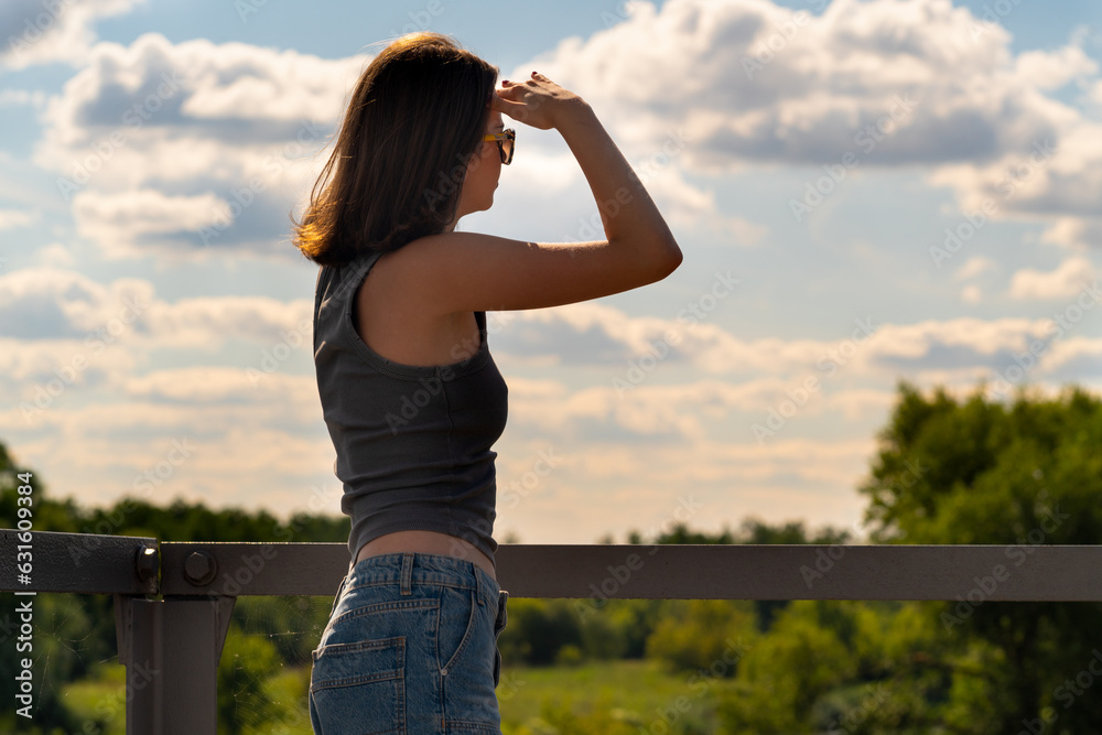 The girl looks into the distance standing on the bridge