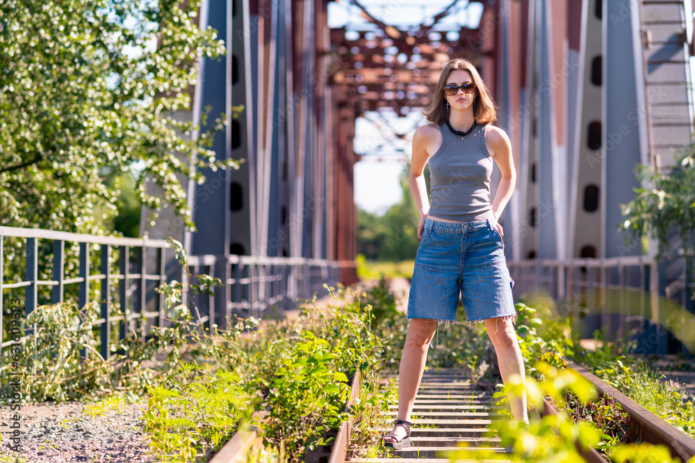 The girl is standing in the middle of the railway tracks