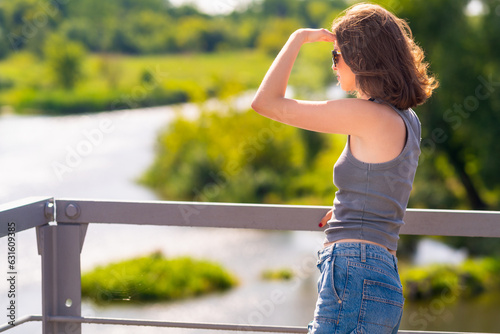 The girl is looking at something from the bridge