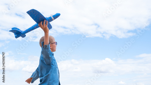 Rear view of a child boy with an airplane dreams of traveling in the summer in nature against the blue sky