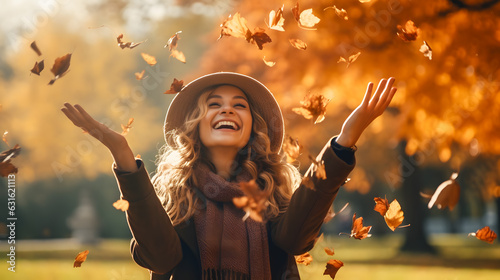 Une femme avec un grand sourire et heureuse d'être en automne en train de jeter des feuilles d'arbres. photo