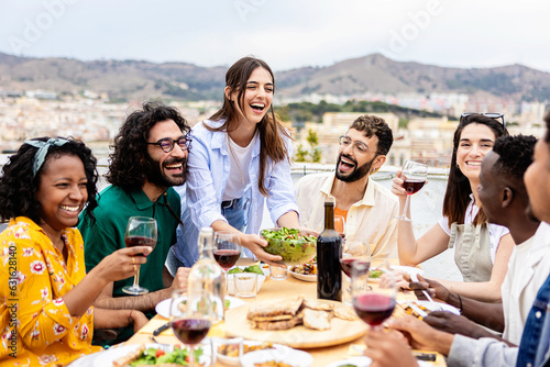 Group of multiracial friends enjoying summer barbecue dinner party at home terrace. 