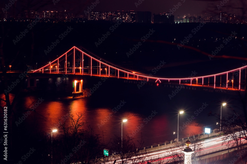 Night city minimal landscape. Dark and tranquil long exposure photography with led illuminated bridge and light reflections in the water. Bridge across the Dnipro river, Kyiv, Ukraine