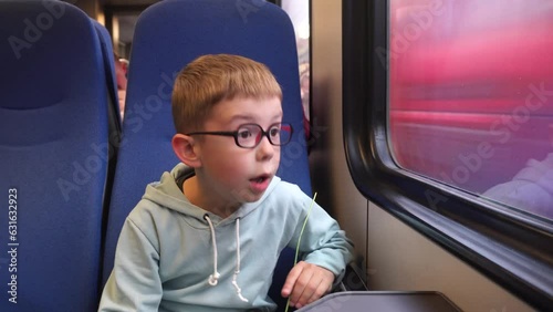 A little boy is traveling on a train and is surprised by an oncoming train speeding past in the window
