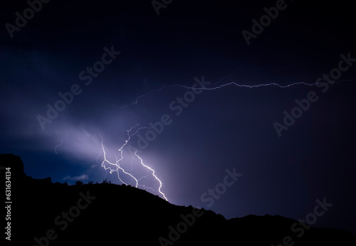 Lightning bolts striking with sihouetted hills at at Lake Mead Nevada