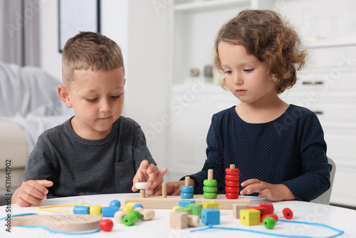 Motor skills development. Little kids playing with stacking and counting game at table indoors