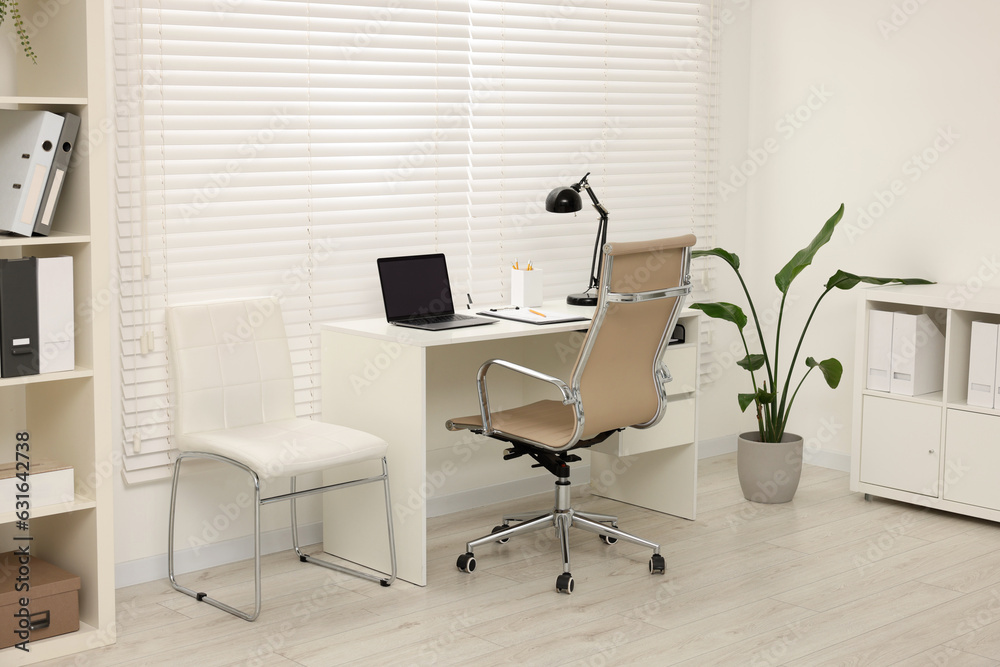 Doctor's workplace. Chairs, laptop and clipboard on white table in clinic Doctor's workplace. Chairs, laptop and clipboard on white table in clinic