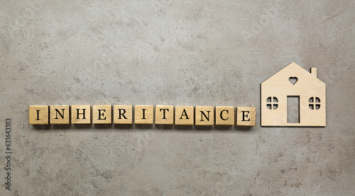 Slika na platnu Word Inheritance made with wooden cubes and house model on grey background, flat