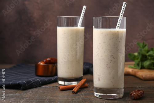 Glasses of delicious date smoothie, dried fruit and cinnamon sticks on wooden table, closeup. Space for text