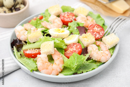 Delicious Caesar salad with shrimps on light table, closeup