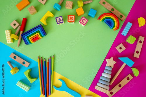 Wooden kids toys on green magenta paper. Educational toys blocks, pyramid, pencils, numbers. Toys for kindergarten, preschool or daycare. Copy space for text. Top view 