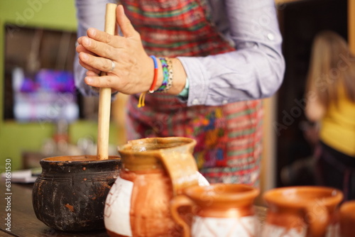Tourist making hot chocolate in a clay pot with a traditional molinillo whisk in Guatemala photo