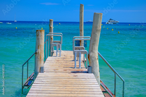 Wooden pier and crystal clear blue water of legendary Pampelonne beach near Saint-Tropez, summer vacation on French Riviera, France