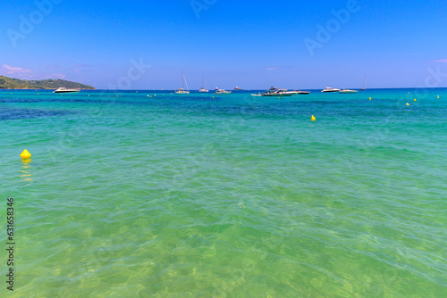 Crystal clear blue water and boats on legendary Pampelonne beach near Saint-Tropez, summer vacation on white sandy beach of French Riviera, France