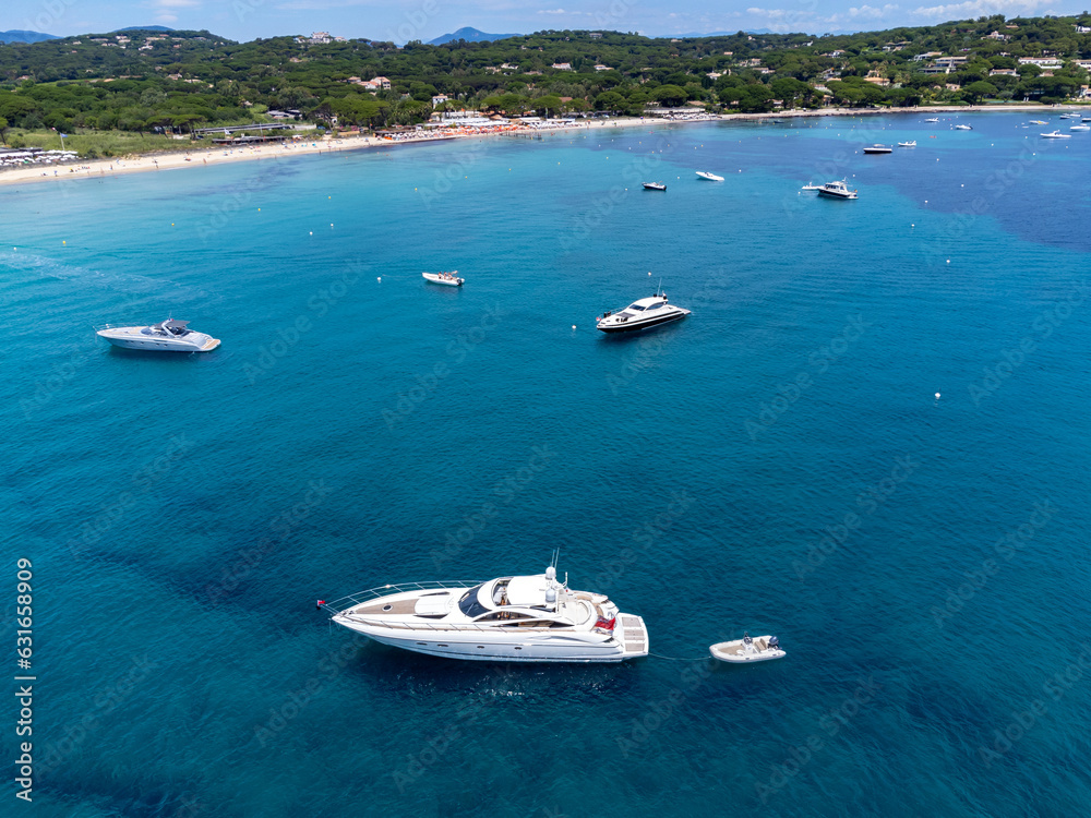 Aerial view on boats, crystal clear blue water of legendary Pampelonne beach near Saint-Tropez, summer vacation on white sandy beach of French Riviera, France