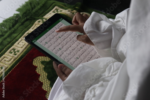 Muslim girl reading electronic Quran on tablet
 photo