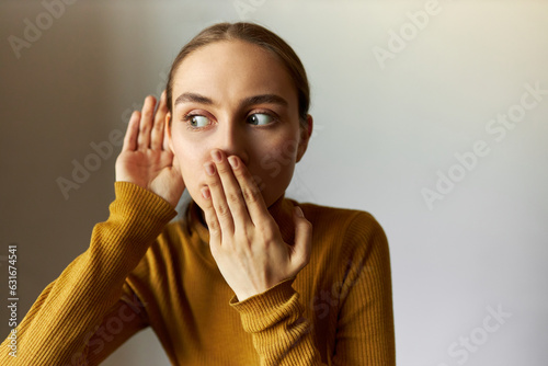Obraz na plátne Horizontal portrait of shocked girl covering mouth looking aside with big round eyes eavesdropping rumors or gossips, after hearing shocking news