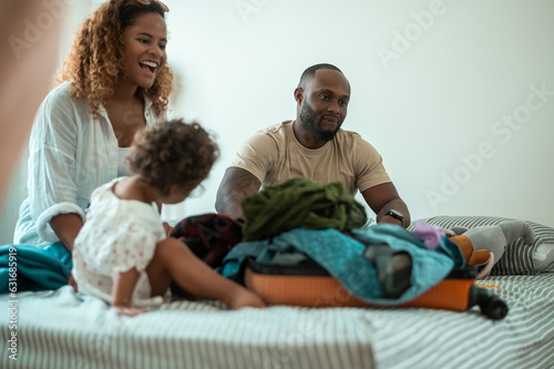 Happy African American Parents with little daughters packing holiday bag of vacation , happy family travel concept