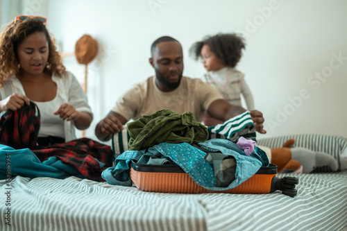 Happy African American Parents with little daughters packing holiday bag of vacation , happy family travel concept