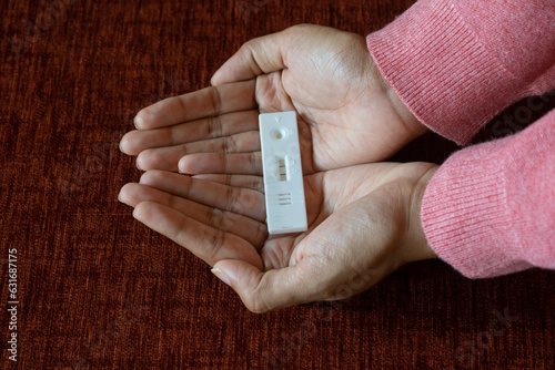 Hands of a woman holding home pregnancy test kit showing positive results. Fertility, conception, pregnant, missed periods, baby, womb, mother, gynaecologist, obstetrician, sonography, ultrasound, sex