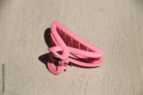 Pink hair clip made of plastic with reflections and shadows for those with long hair and looks fashionable, women's accessories taken close up 