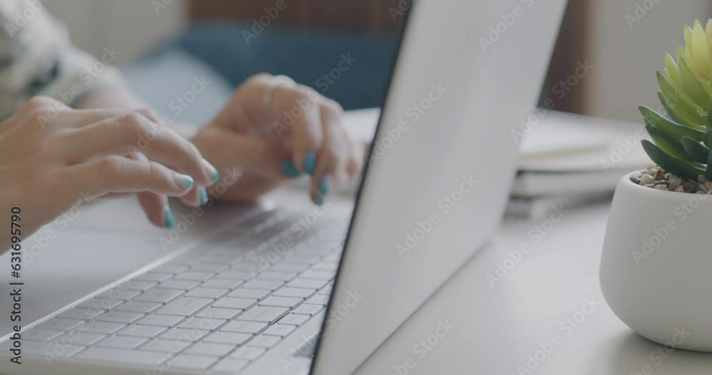 Close-up of female hands typing with laptop working with computer against blurred domestic background