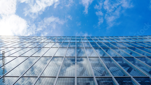 View upwards of a transparent glass facade of a modern office building reflecting the sky