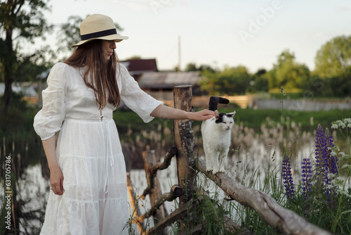 Young woman in a dress and hat in a lupine field, rustic style, photo
