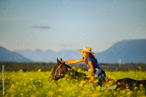 Girl laughing on horseback through a canola field in Montana photo