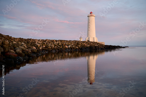 Lighthouse on shore near water in evening photo