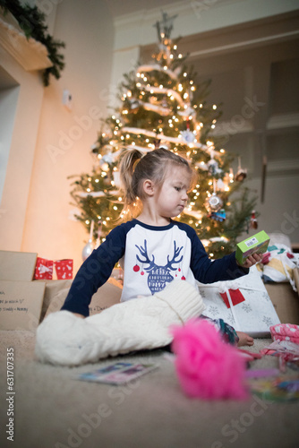 Young girl opens her stocking under the Christmas tree photo