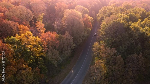 Aerial view of rural road with white car in yellow and orange au