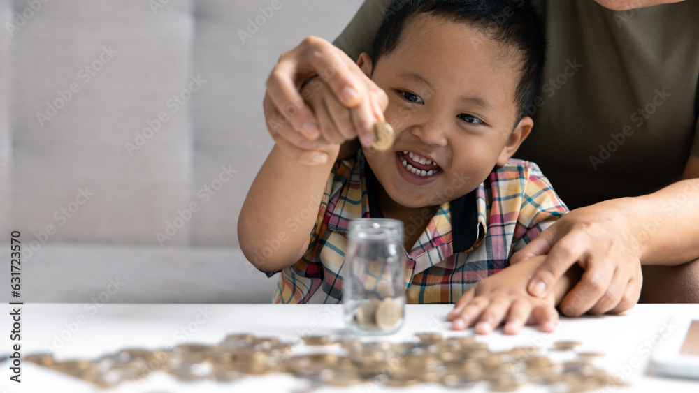 Happy Asian kid and mom saving money together, putting cash into piggy bank. Mother playing with child on heating floor at home, teaching little son to invest money, planning future. Happy Asian kid and mom saving money together, putting cash into piggy bank. Mother playing with child on heating floor at home, teaching little son to invest money, planning future.