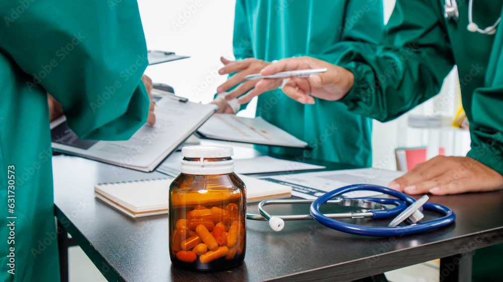 Multiracial medical team having a meeting with doctors in white lab coats and surgical scrubs seated at a table discussing a patients records