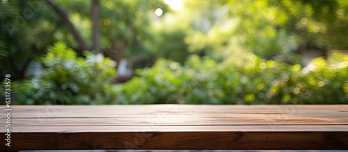 An empty wooden table is placed outdoors in a garden, with a blurred background. The table is clean and offers ample space for text, making it suitable for marketing and promotional purposes. It