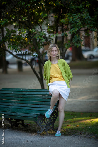 Obraz na płótnie A woman in a skirt sits on a park bench. w salonie
