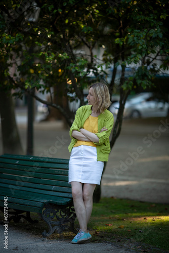 Obraz na płótnie A woman sits waiting for her prince on a bench in a city park. w salonie